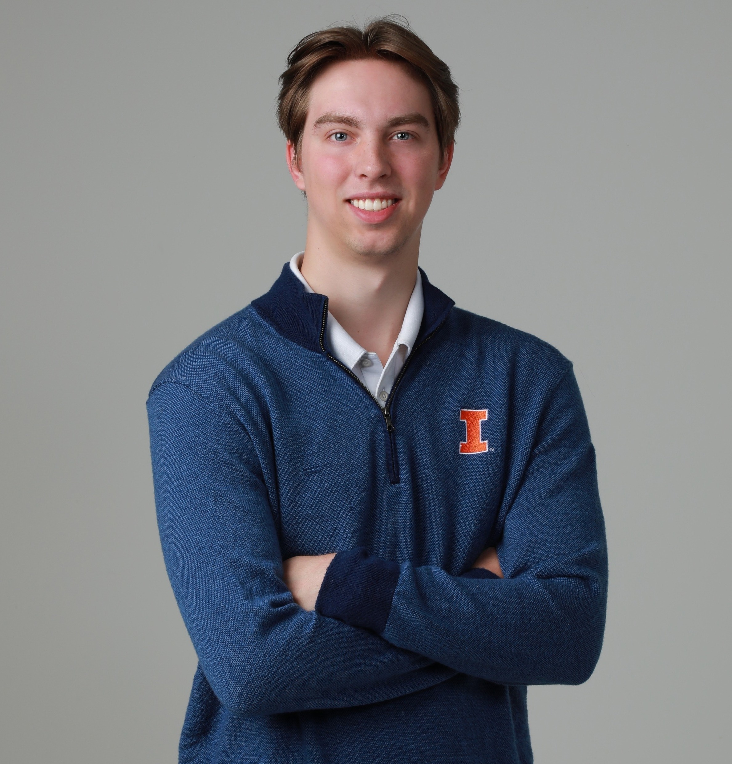 Matt Isaacs standing with arms folded and smiling against gray background.